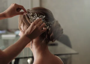 Hairstylist adding a delicate bridal headpiece to a sophisticated wedding updo at wedding hair trial
