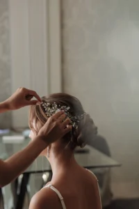 Hairstylist adding a delicate bridal headpiece to a sophisticated wedding updo