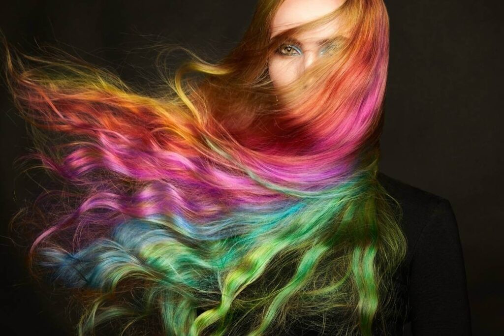 Wavy, rainbow coloured hair blows to the left, displaying all colours - bold dyeing hair
