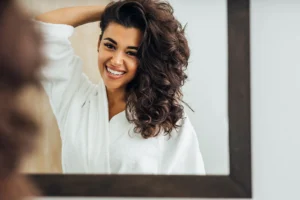 Woman admiring her curly, voluminous hair in a mirror