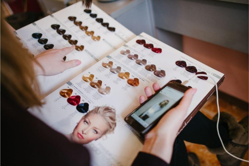 Client comparing an Instagram picture to swatches in a hairdresser's permanent hair colour book.