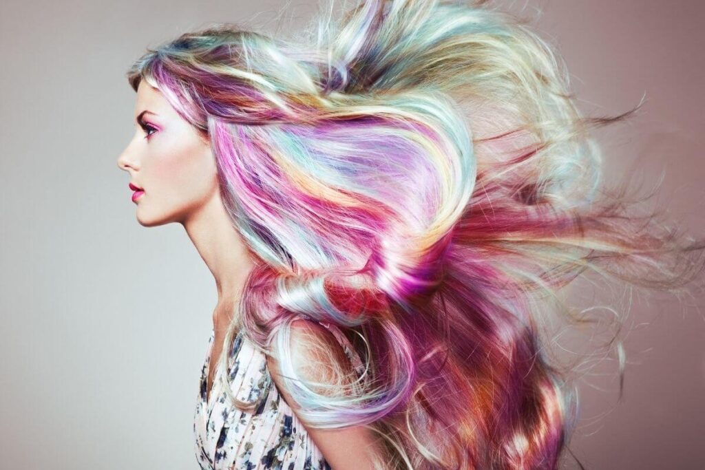 Model with long rainbow semi permanent hair colour blowing in the wind