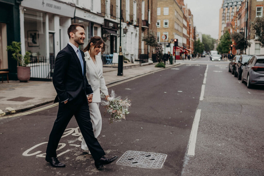 Bride white wedding dress and groom black suit walking in london