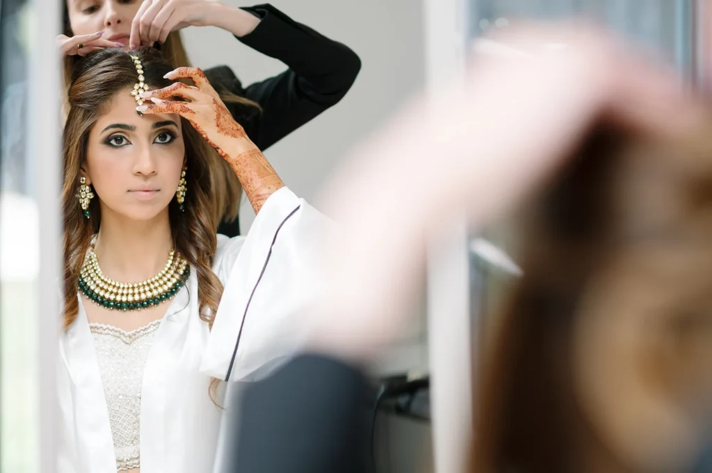 Bride adjusting her headpiece in the mirror during wedding preparations