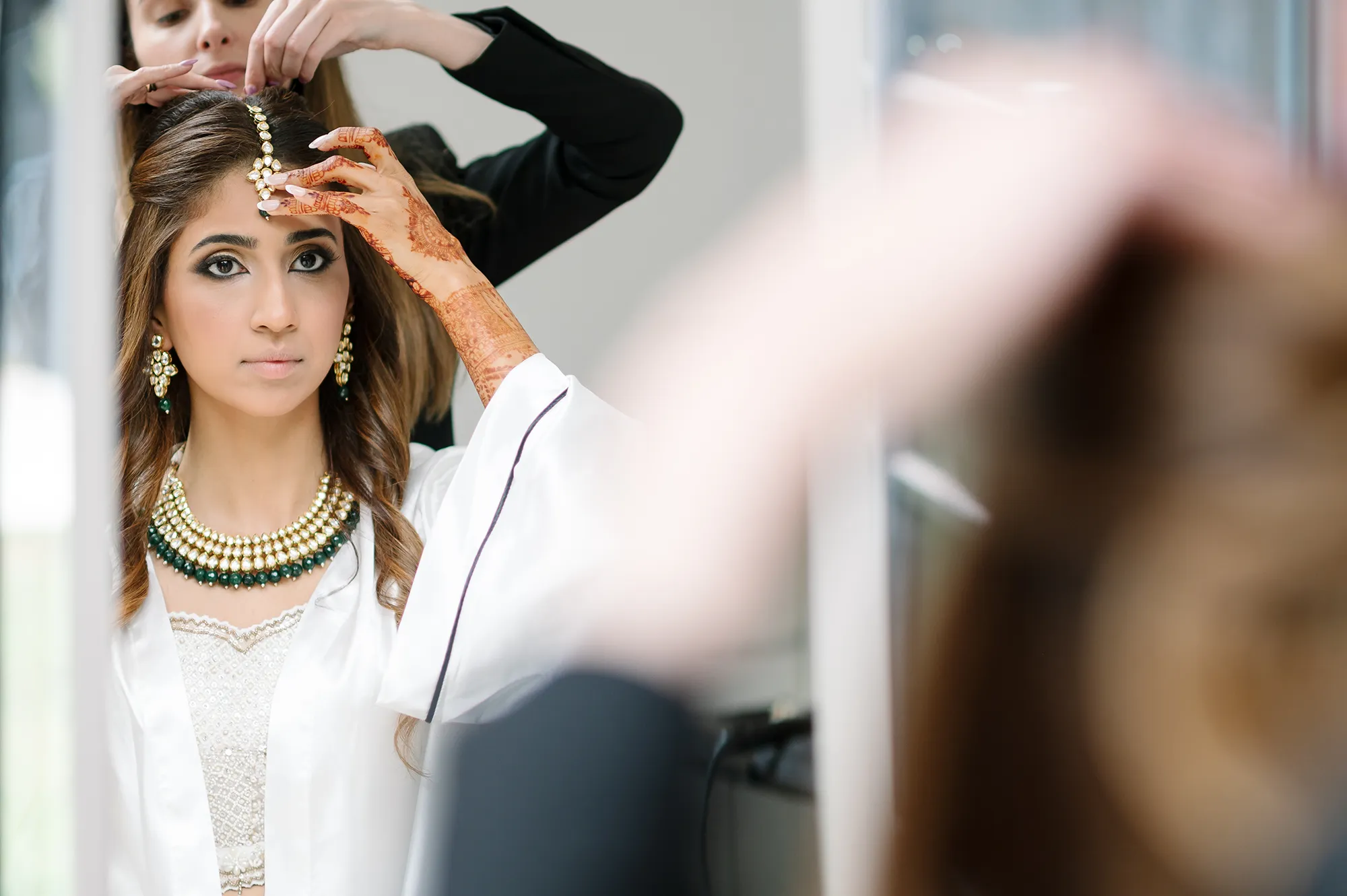 Bride adjusting her headpiece in the mirror during wedding preparations