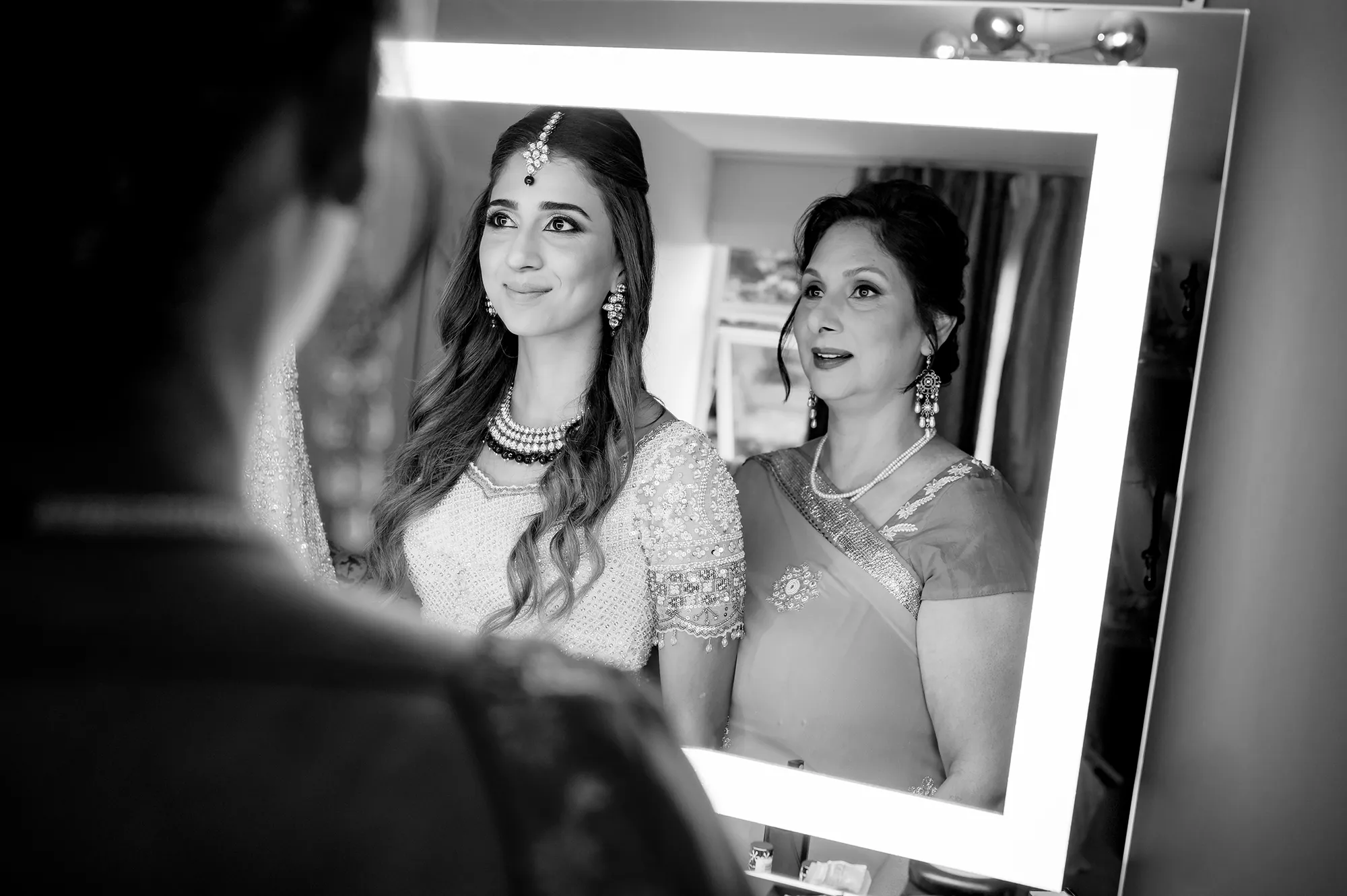 Bride and mother sharing a candid emotional moment in front of a mirror before the ceremony at Hampton Court House Wedding