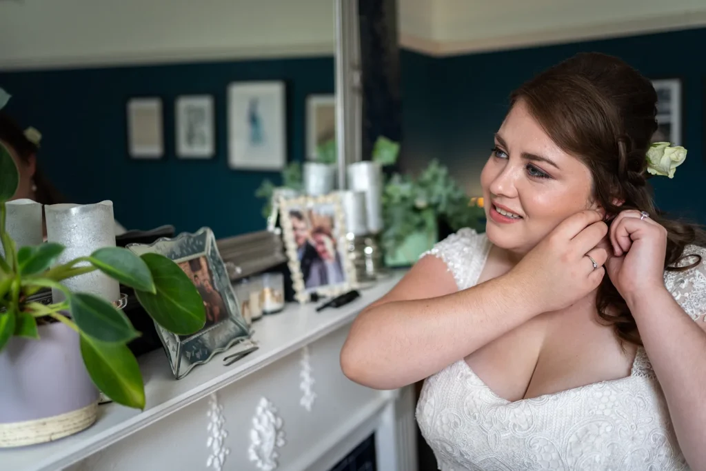 Bride Ellen smiling while adjusting her earring, with a serene decor in the background