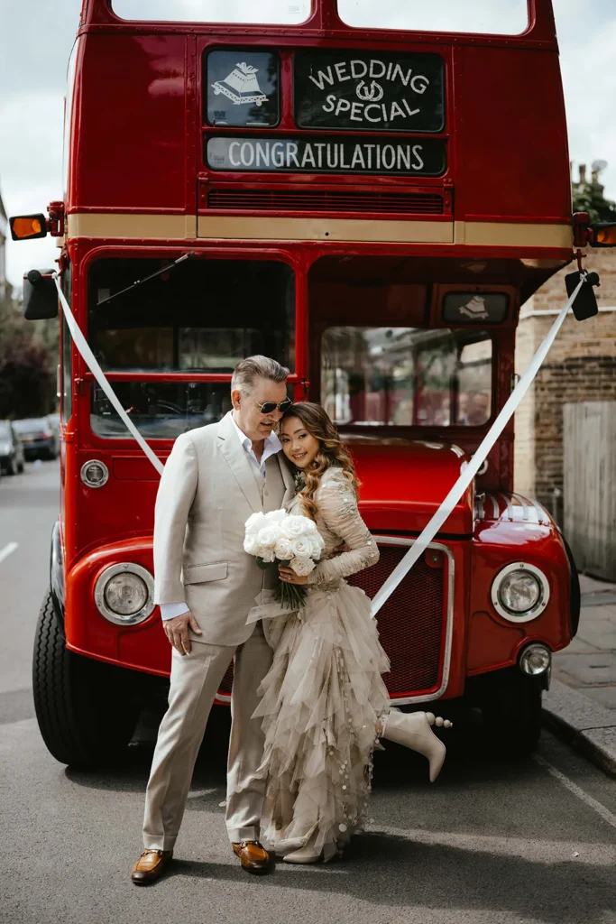 Newlyweds Dannah and David posing in front of a vintage red bus.