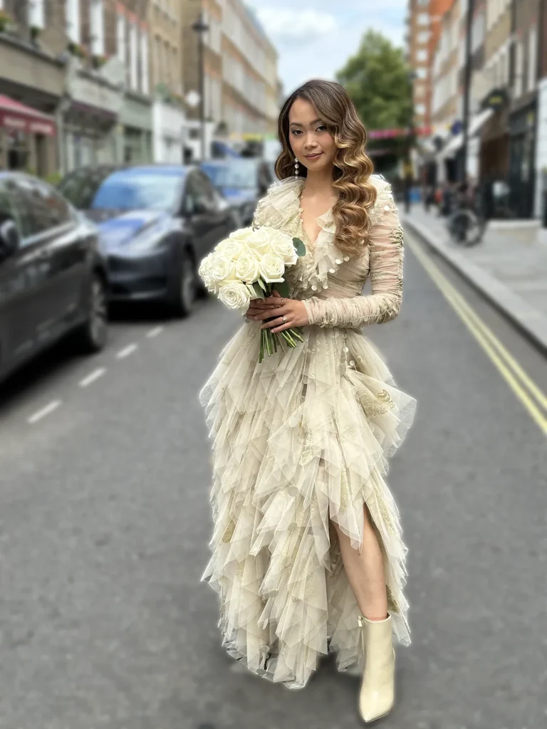 Bride Dannah standing on a bustling London street with a bouquet of roses.