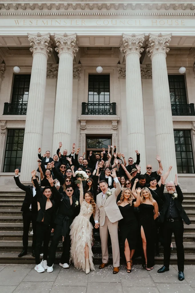 Bride Dannah, groom David, and guests celebrating on the steps of The Old Marylebone Town Hall in London.
