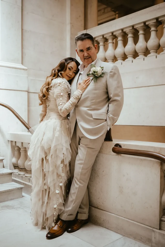 Bride Dannah and groom David in a loving embrace by a marble staircase in London.