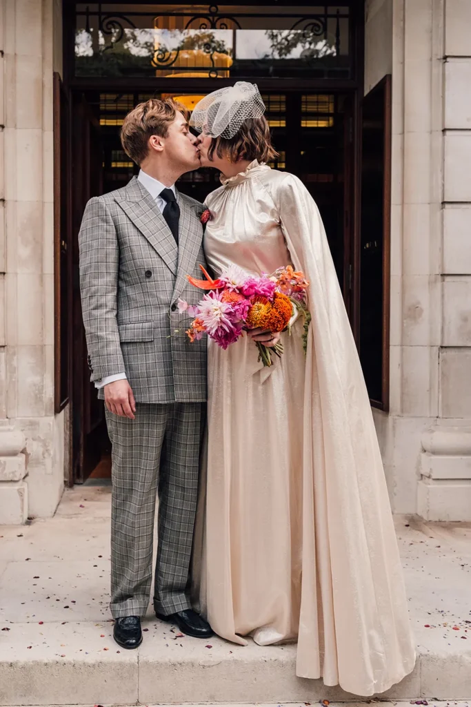 Bride Camilla and Nathan sharing a kiss at London wedding entrance.