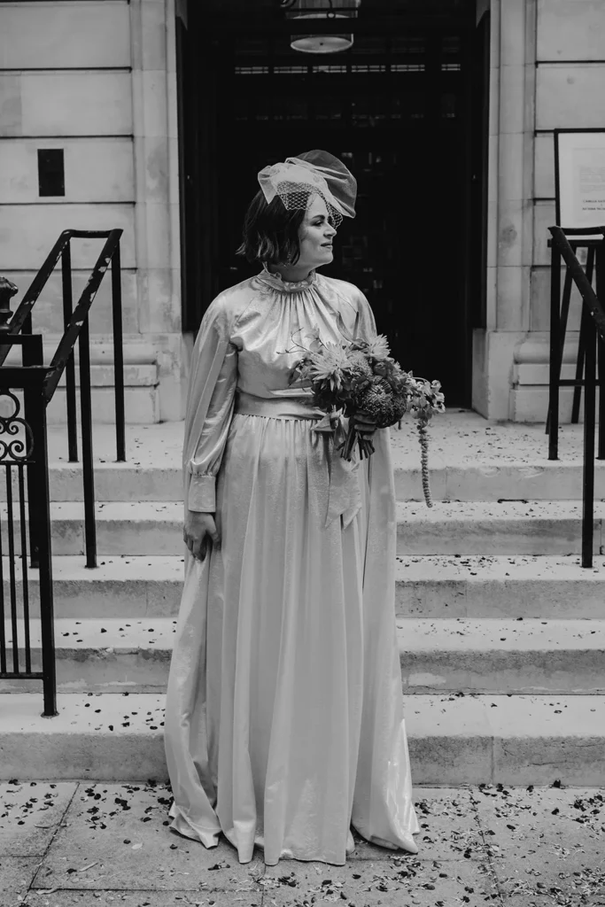 Bride Camilla in her wedding dress standing on steps outside London venue