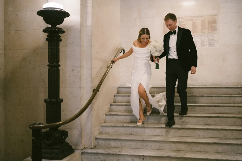 Bride and groom descending stairs together in London Marylebone Town Hall