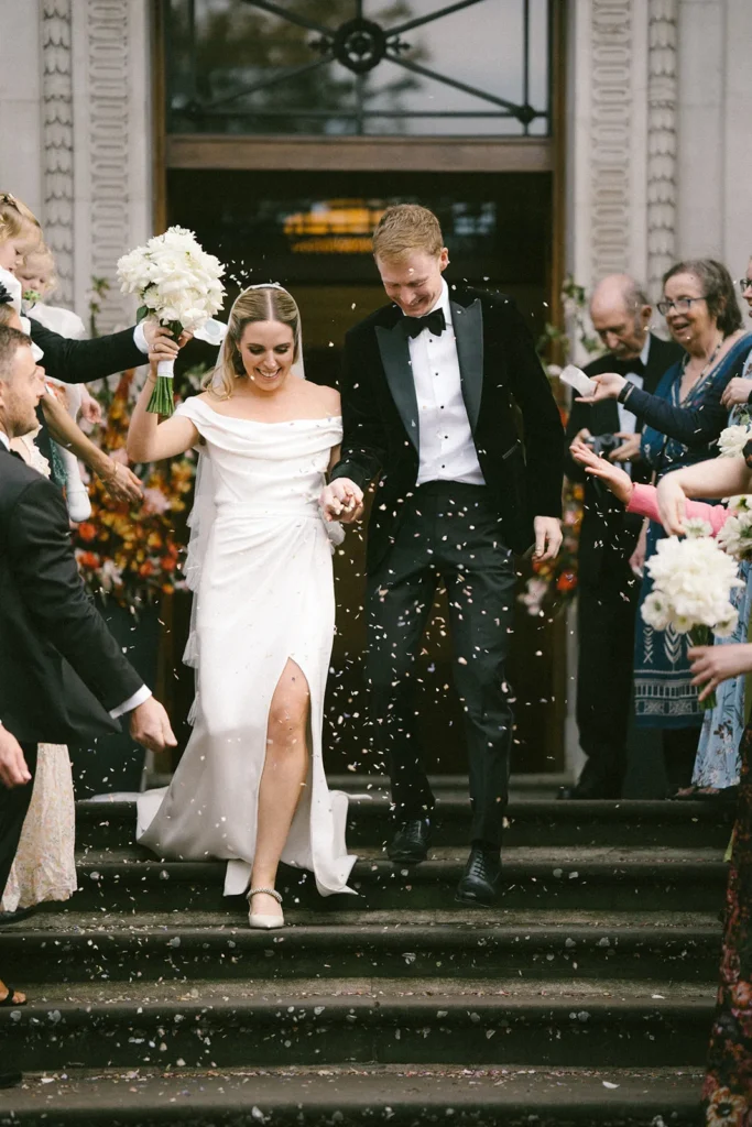 Bride and groom joyfully exiting wedding venue Marylebone Town Hall with confetti in London