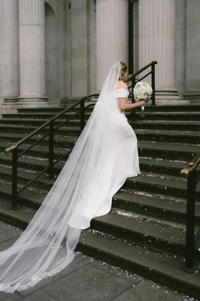 Bride ascending the steps of Marylebone Town Hall in London with her bouquet