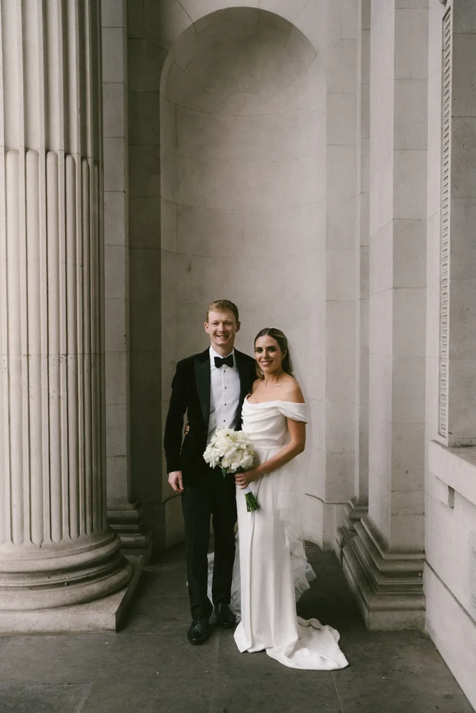 Elegant bride and groom posing under the columns of a historic the Old Marylebone Town Hall