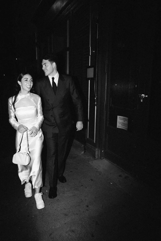 Bride and groom holding hands while walking down a charming London street