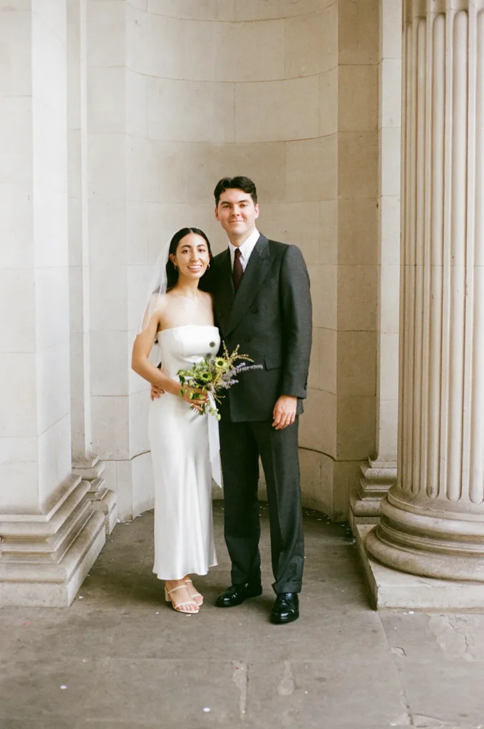 Bride and groom standing together in front of classical architecture in London at the Old Marylebone Town Hall