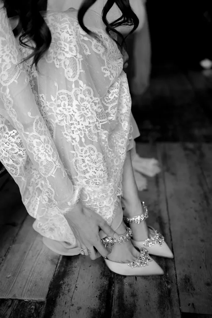 Bride adjusting crystal-embellished heels on wedding day in London