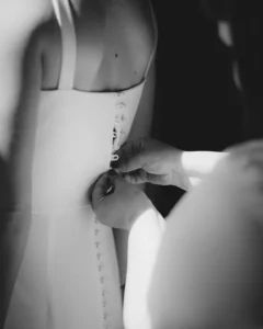 Close-up of a wedding dress being buttoned before the ceremony