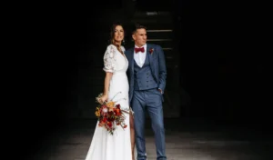 Bride and groom striking a stylish pose in front of rustic backdrop