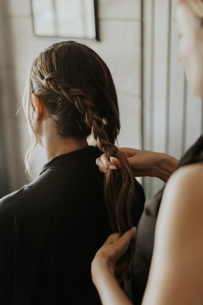 Bride getting her hair braided before boho chic wedding ceremony