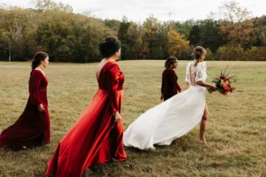 Bridesmaids and bride walking across the field in flowing dresses