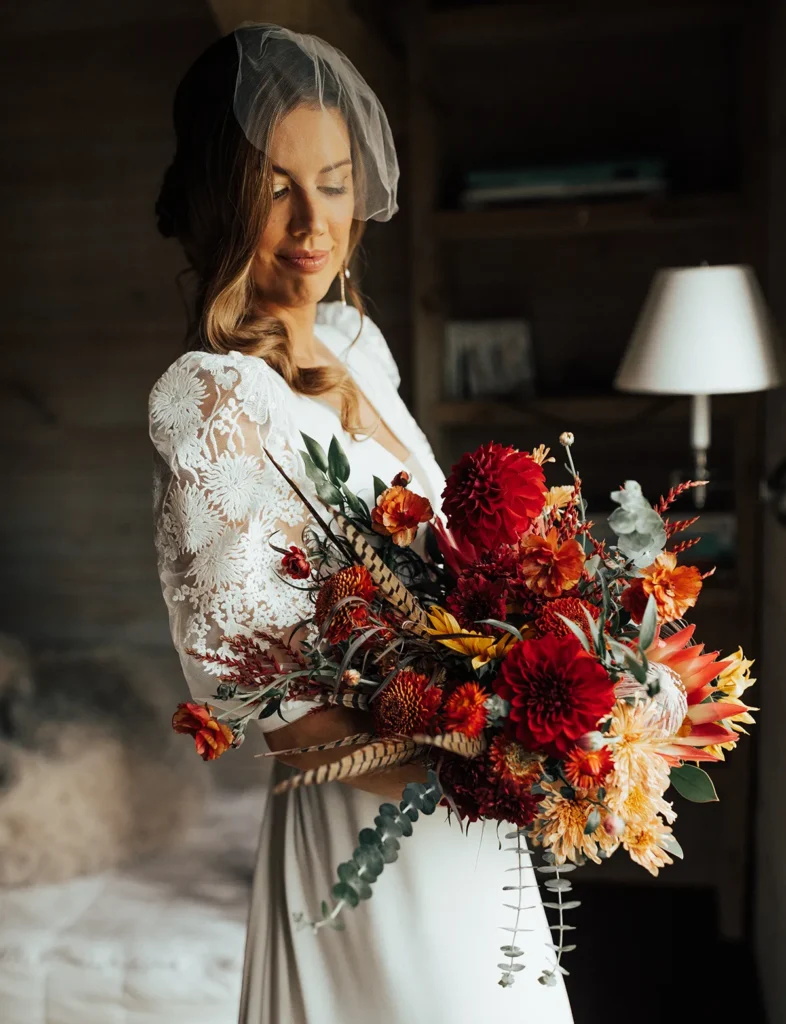 Bride holding vibrant boho chic bouquet inside rustic venue