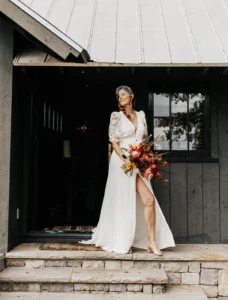 Bride stepping outside, holding bouquet before boho chic wedding