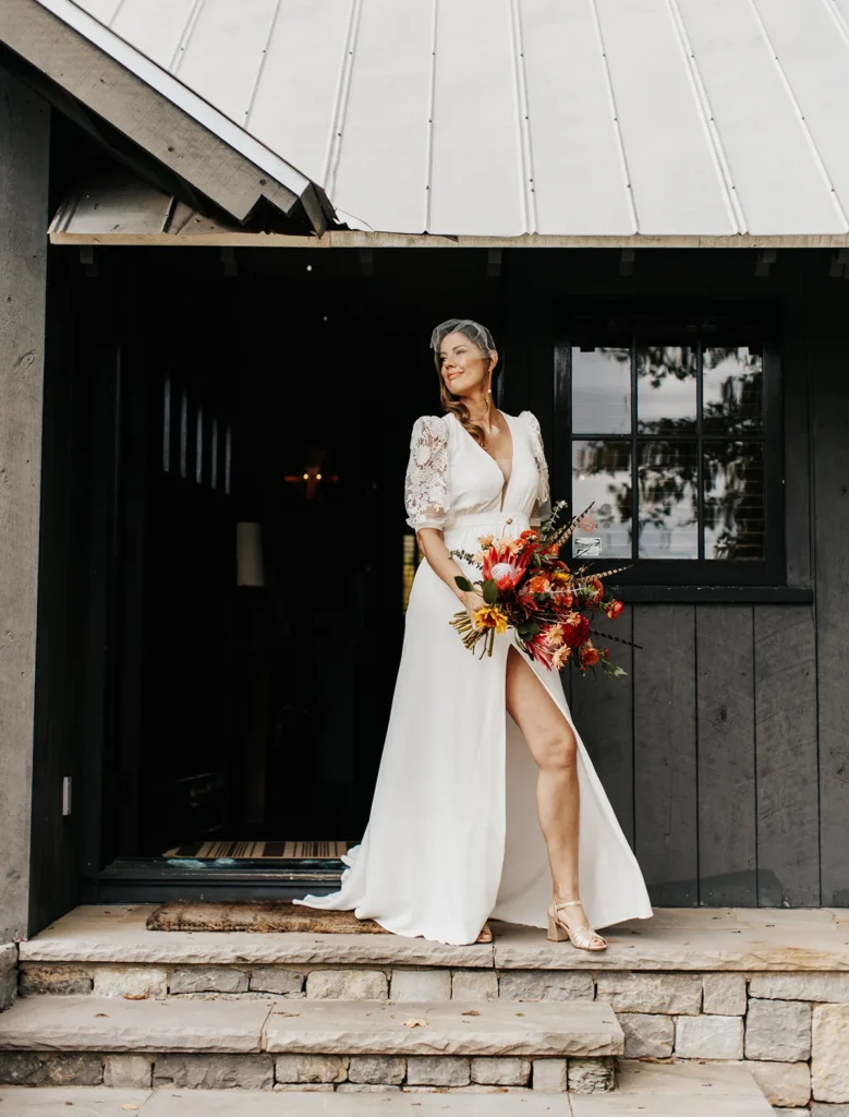 Bride stepping outside, holding bouquet before boho chic wedding