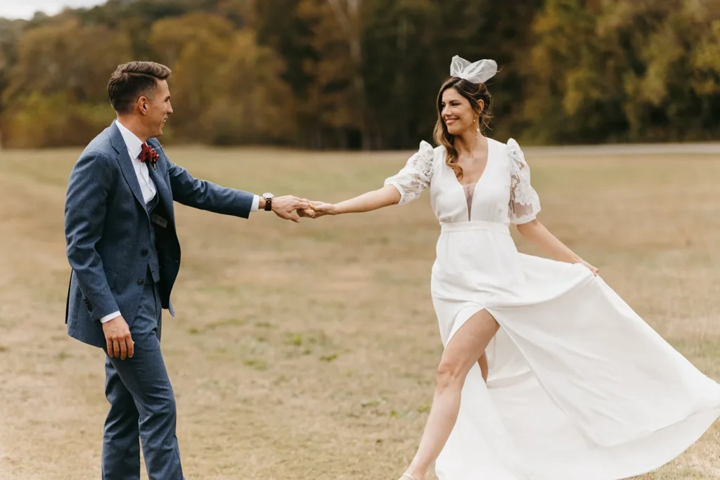 Bride and groom holding hands in open field during boho chic wedding