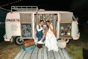 Bride and groom sitting in vintage camper after boho chic wedding