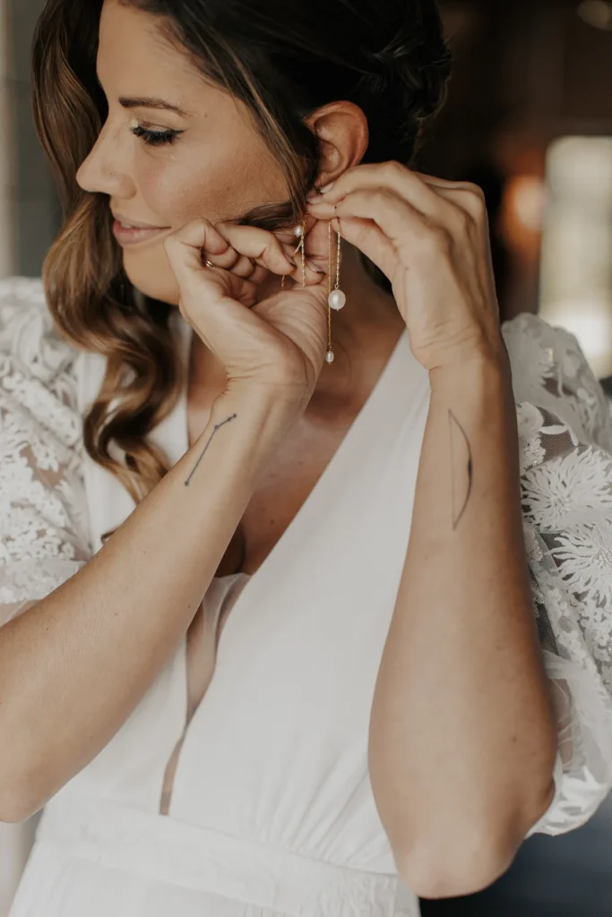 Bride adjusting earrings, showing constellation tattoo on her wrist