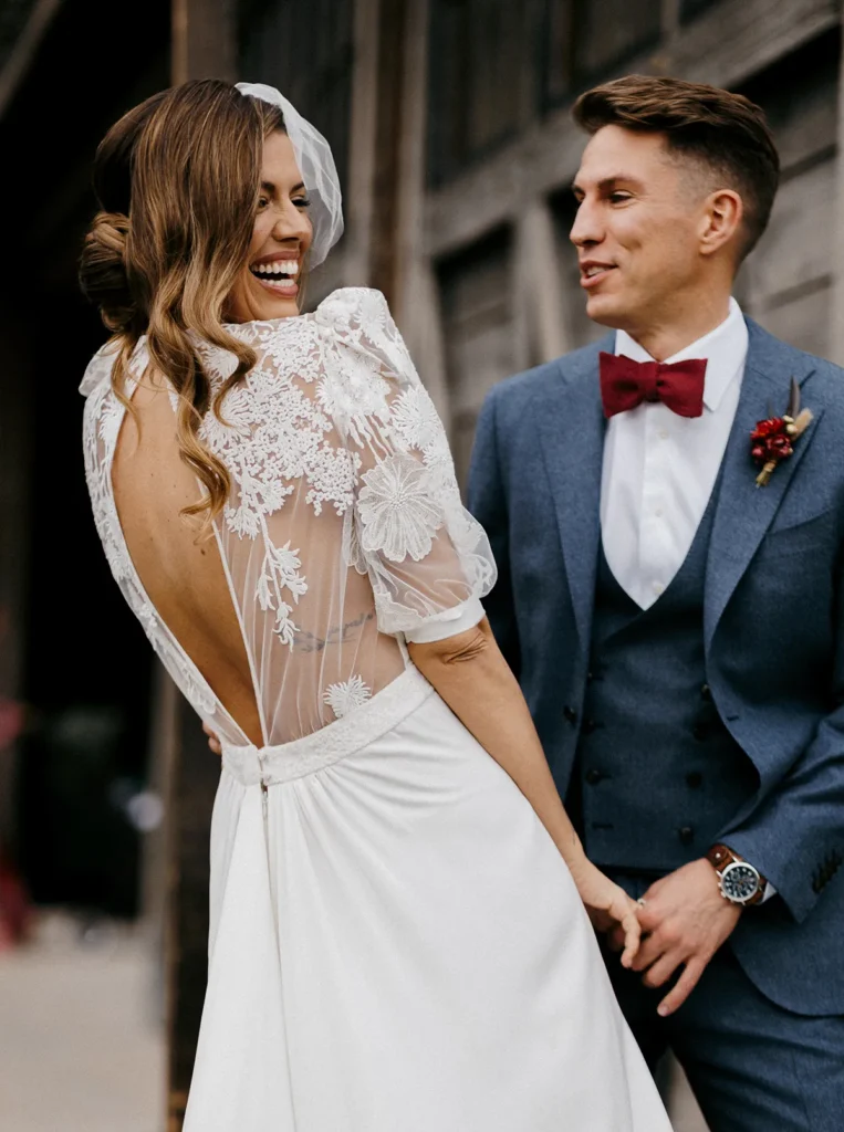 Bride laughing with groom in open-back boho chic wedding dress