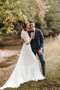 Bride and groom posing outdoors for wedding photo by a river