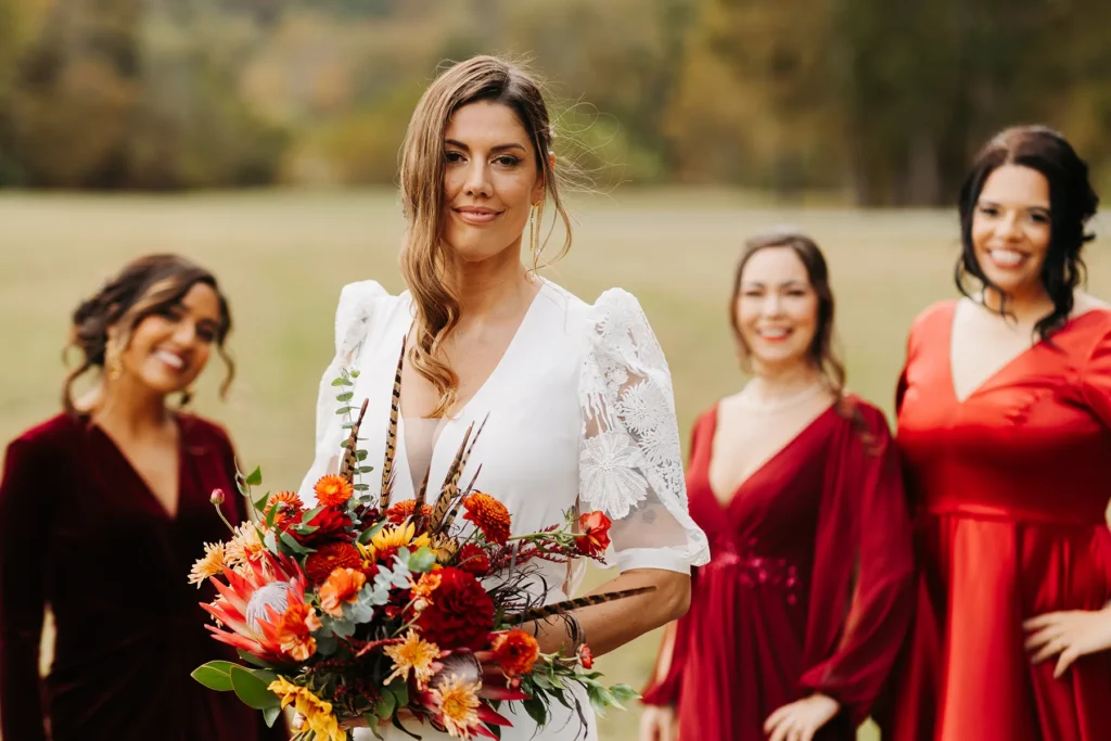 Bride standing with bridesmaids in red dresses at outdoor wedding