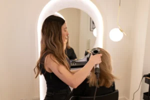 Bridal hairstylist blow-drying bride’s hair in preparation for wedding photoshoot