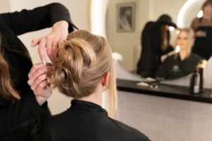 Bridal stylist adjusting an elegant updo hairstyle during wedding preparation