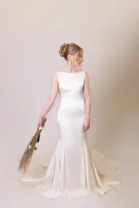 Bride in sleek white gown with updo hairstyle holding natural bouquet