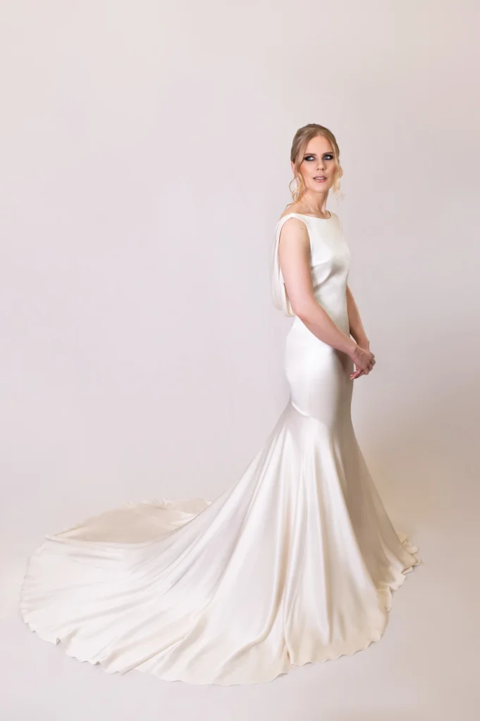 Bridal gown with a long flowing train in ivory satin