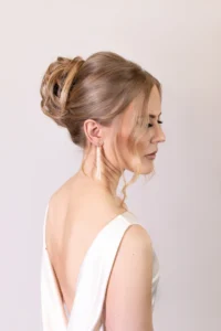 Bridal updo with soft blonde curls and side bangs for a classic wedding look