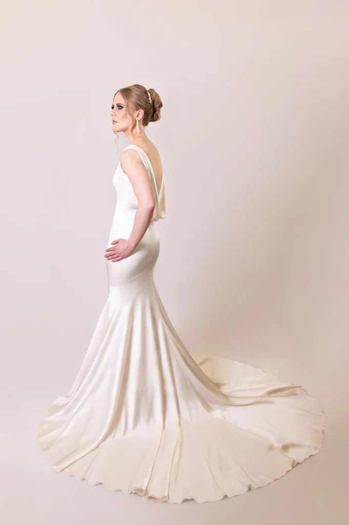 Side view of a bride in a flowing satin gown and updo hairstyle