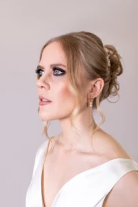 Bride posing in a sleek satin gown with an elegant updo for a bridal shoot