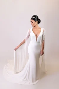 Bride in full-length modern wedding gown with sheer cape