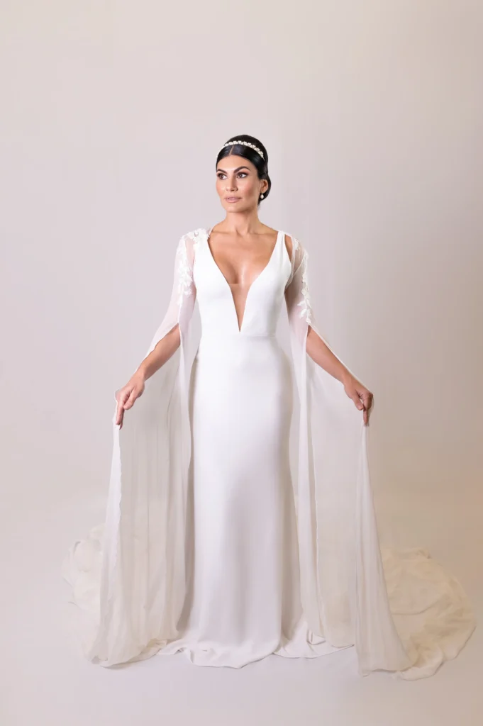 Back view of bride’s gown with an open-back design and flowing cape