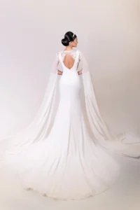 Back view of bride wearing a gown with a low-cut back and long cape sleeves