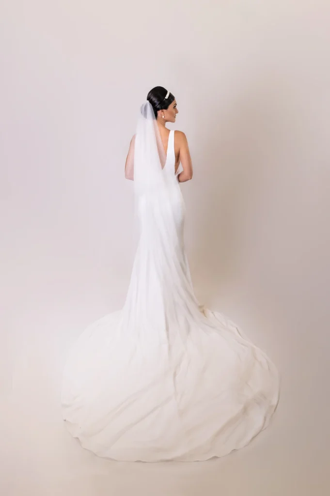 Bride in a long veil and elegant sleek low bun with a flowy train