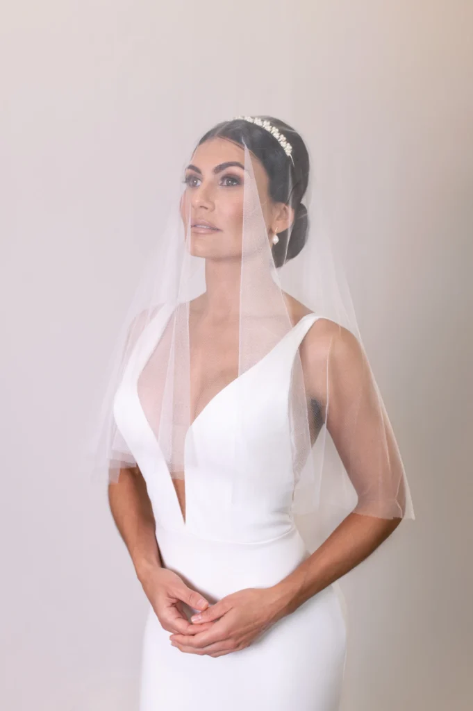 Bride wearing a short veil over her face with a sleek low bun hairstyle