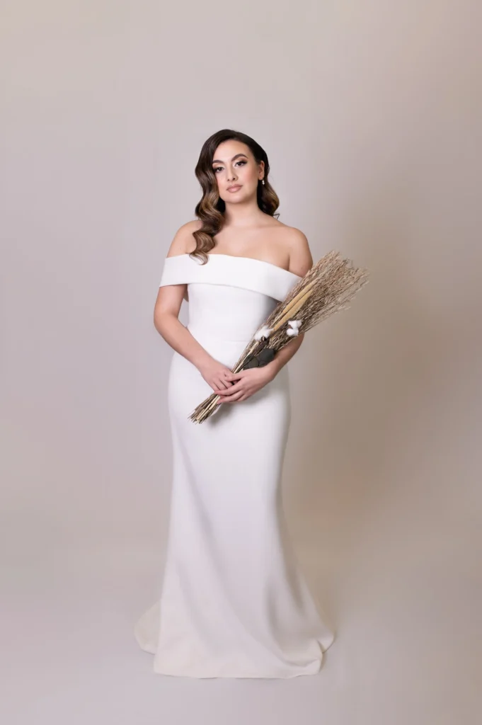 Bride in an off-the-shoulder wedding gown holding a dried flower bouquet